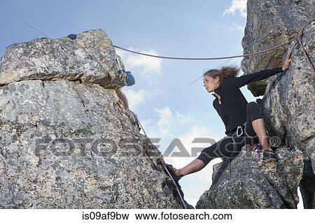 Stock Photo - Young female rock climber sitting on rock ledge. Fotosearch