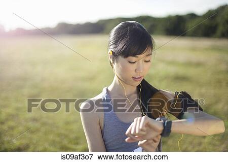 Stock Photo - Young female runner checking watch for time. Fotosearch