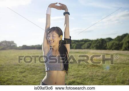 Stock Photograph - Young female runner stretching arms and warming up. Fotosearch