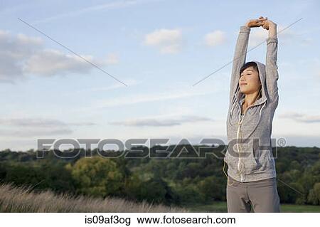 Stock Image - Young female runner stretching arms. Fotosearch