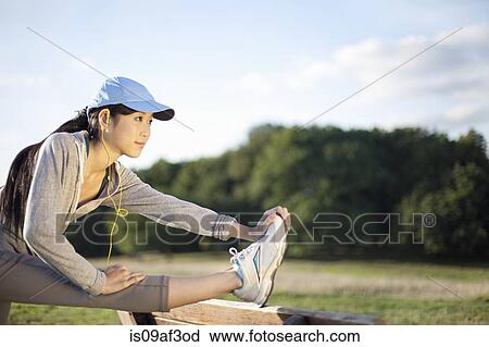 Stock Image - Young female runner stretching legs. Fotosearch