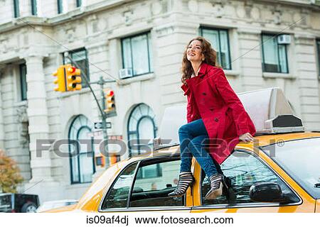 Young female tourist sitting on top of yellow cab, New York City, USA View Large Photo Image Stock Image - Young female tourist sitting on top of yellow cab, New York City, USA. Fotosearch