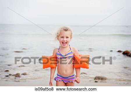 Stock Photo - Young girl with armbands on the beach. Fotosearch