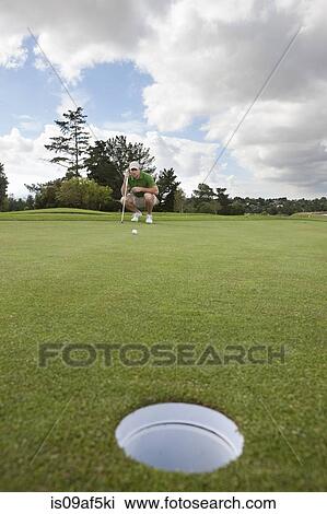 Young male golfer lining up the ball on the green View Large Photo Image Stock Image - Young male golfer lining up the ball on the green. Fotosearch