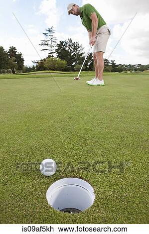 Young male golfer playing the ball on the green View Large Photo Image Stock Image - Young male golfer playing the ball on the green. Fotosearch