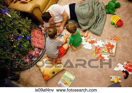 Young man and nephews playing with jigsaw puzzles on floor View Large Photo Image Stock Photo - Young man and nephews playing with jigsaw puzzles on floor. Fotosearch