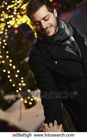 Young man holding hands with girlfriend on city street View Large Photo Image Stock Photo - Young man holding hands with girlfriend on city street. Fotosearch