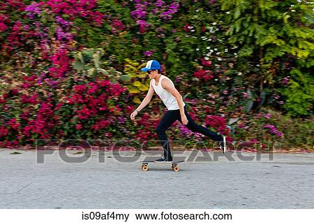 Young man skateboarding along suburban sidewalk View Large Photo Image Stock Photo - Young man skateboarding along suburban sidewalk. Fotosearch