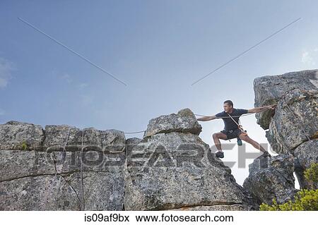 Young man stepping and reaching on rock climb View Large Photo Image Stock Photo - Young man stepping and reaching on rock climb. Fotosearch