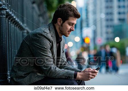 Stock Photo - Young man waiting on city street, Toronto, Ontario, Canada. Fotosearch
