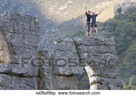Stock Photography - Young rock climbing couple celebrating on rock formation. Fotosearch