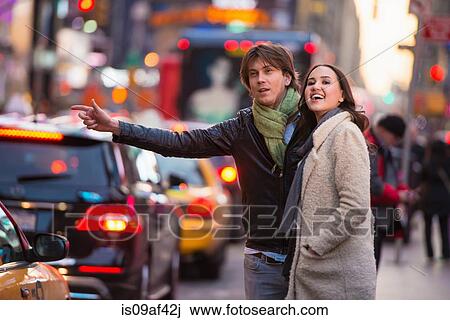 Stock Image - Young tourist couple hailing a cab, New York City, USA. Fotosearch