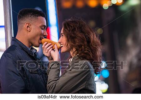 Stock Photography - Young tourist couple sharing hotdog, New York City, USA. Fotosearch