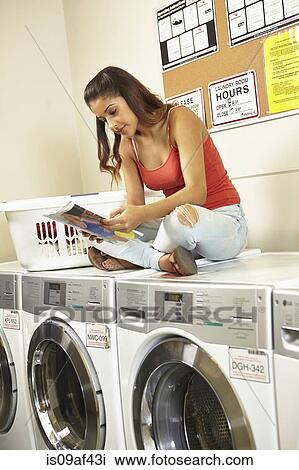 Young woman doing laundry in laundrette View Large Photo Image Stock Image - Young woman doing laundry in laundrette. Fotosearch