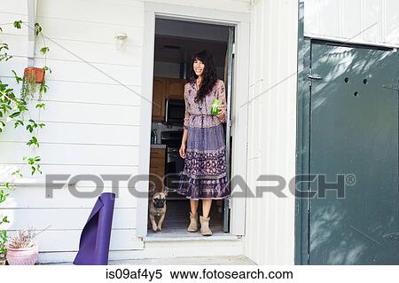 Stock Photography - Young woman in doorway with vegetable juice. Fotosearch