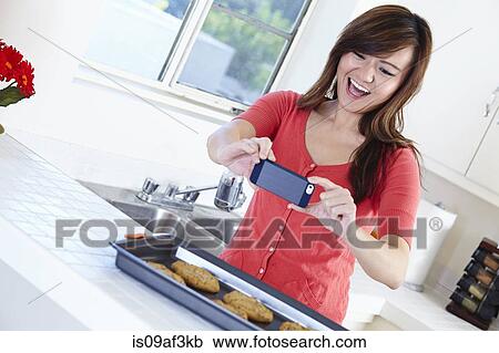 Young woman in kitchen preparing food and taking self portrait View Large Photo Image Stock Image - Young woman in kitchen preparing food and taking self portrait. Fotosearch
