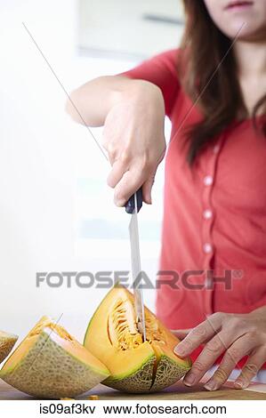 Young woman in kitchen slicing melon View Large Photo Image Stock Photo - Young woman in kitchen slicing melon. Fotosearch