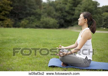 Young woman in park practicing yoga lotus position View Large Photo Image Stock Image - Young woman in park practicing yoga lotus position. Fotosearch