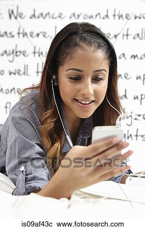 Stock Image - Young woman listening to music in bedroom. Fotosearch