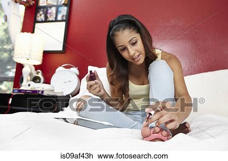 Young woman painting nails on bed View Large Photo Image Stock Image - Young woman painting nails on bed. Fotosearch