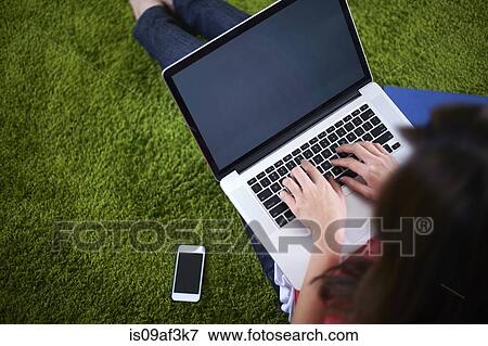 Young woman sitting on rug using laptop View Large Photo Image Stock Photo - Young woman sitting on rug using laptop. Fotosearch