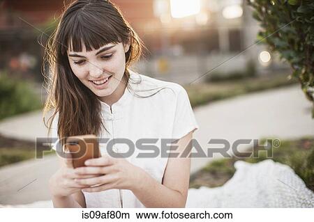 Picture - Young woman texting on cellphone. Fotosearch