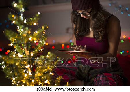 Stock Image - Young woman using digital tablet and preparing for christmas. Fotosearch