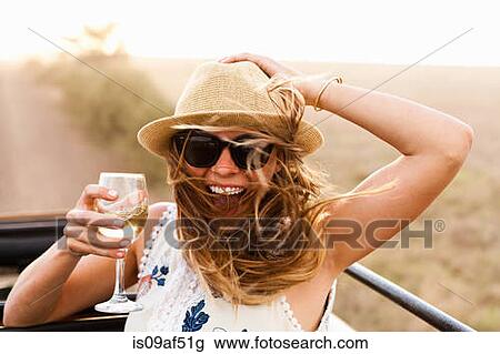 Stock Image - Young woman wearing hat holding glass of wine. Fotosearch