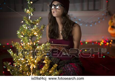 Stock Image - Young woman with digital tablet preparing for christmas. Fotosearch