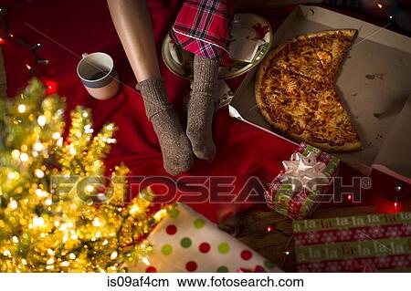 Picture - Young woman's legs amongst christmas gifts and pizza box. Fotosearch