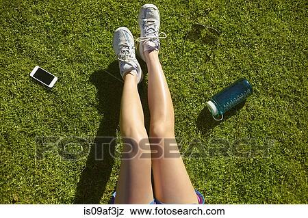 Young woman's legs on sunlit grass in park View Large Photo Image Stock Photo - Young woman's legs on sunlit grass in park. Fotosearch