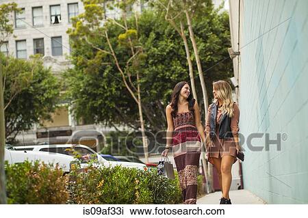Young women walking along pavement View Large Photo Image Stock Image - Young women walking along pavement. Fotosearch