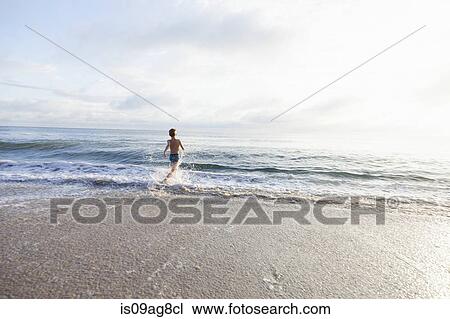 Stock Image - Boy going for swim in sea. Fotosearch