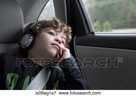 Stock Photo - Boy in back seat of car, wearing headphones. Fotosearch