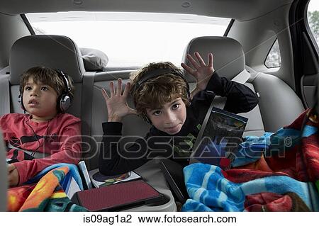Brothers in back seat of car, wearing headphones View Large Photo Image Stock Image - Brothers in back seat of car, wearing headphones. Fotosearch