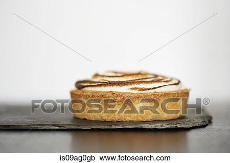 Stock Image - Close up of lemon tart on slate. Fotosearch