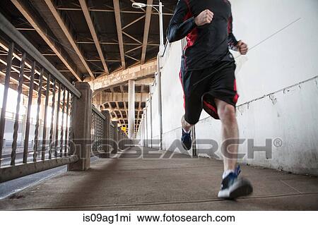 Stock Image - Cropped shot of young man running on city bridge. Fotosearch