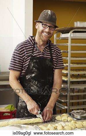 Male baker slicing dough in bakery View Large Photo Image Stock Image - Male baker slicing dough in bakery. Fotosearch