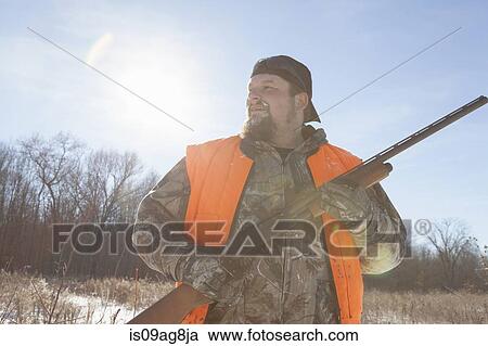 Stock Image - Mid adult man holding shotgun in Petersburg State Game Area, Michigan, USA. Fotosearch