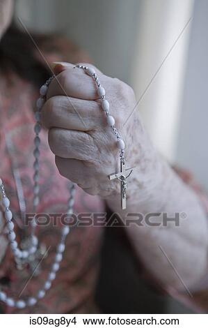 Picture - Senior woman holding rosary. Fotosearch