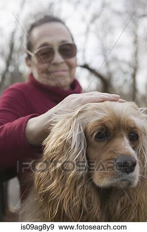 Stock Photo - Senior woman patting dog. Fotosearch