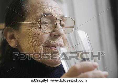 Stock Image - Senior woman with glass of drinking water. Fotosearch