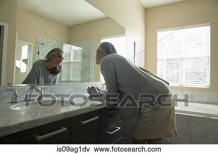 Stock Photo - Woman pondering in front of mirror. Fotosearch