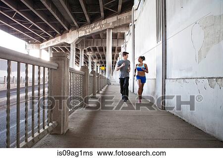 Young couple running on city bridge View Large Photo Image Stock Photograph - Young couple running on city bridge. Fotosearch