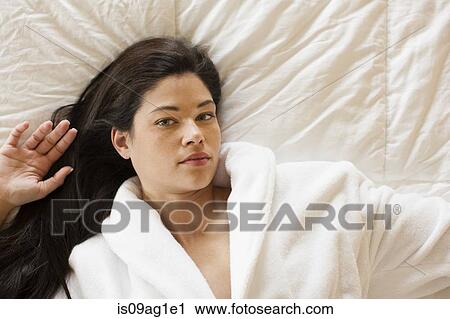 Young woman lying on bed View Large Photo Image Stock Image - Young woman lying on bed. Fotosearch