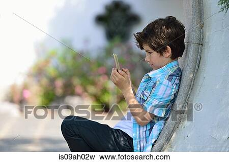 Boy leaning against curved wall texting on cellphone View Large Photo Image Stock Photo - Boy leaning against curved wall texting on cellphone. Fotosearch