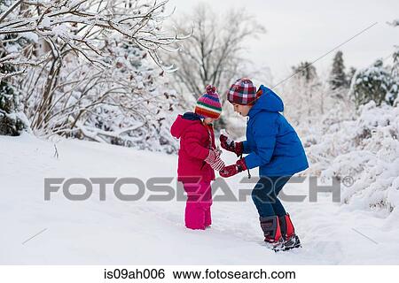 Brother showing icicles to sister whilst out in snow View Large Photo Image Stock Photograph - Brother showing icicles to sister whilst out in snow. Fotosearch