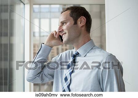 Stock Photo - Businessman chatting on mobile phone in office. Fotosearch