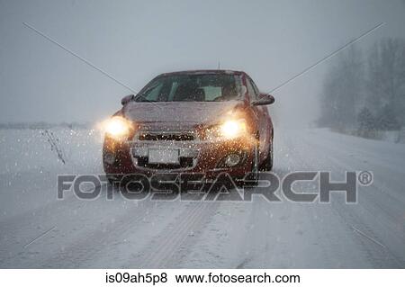 Stock Photo - Car with headlights on driving along foggy snow covered road. Fotosearch