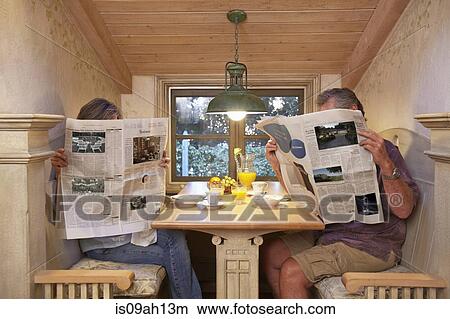 Couple at breakfast table, ignoring each other, reading newspapers View Large Photo Image Picture - Couple at breakfast table, ignoring each other, reading newspapers. Fotosearch